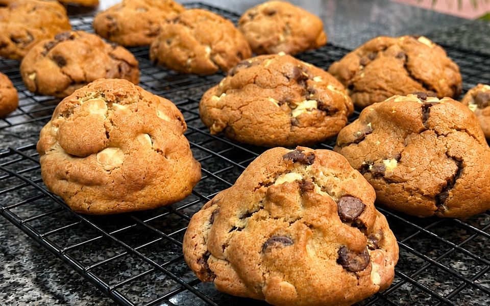 Cookies em primeiro plano, com uma assadeira ao fundo