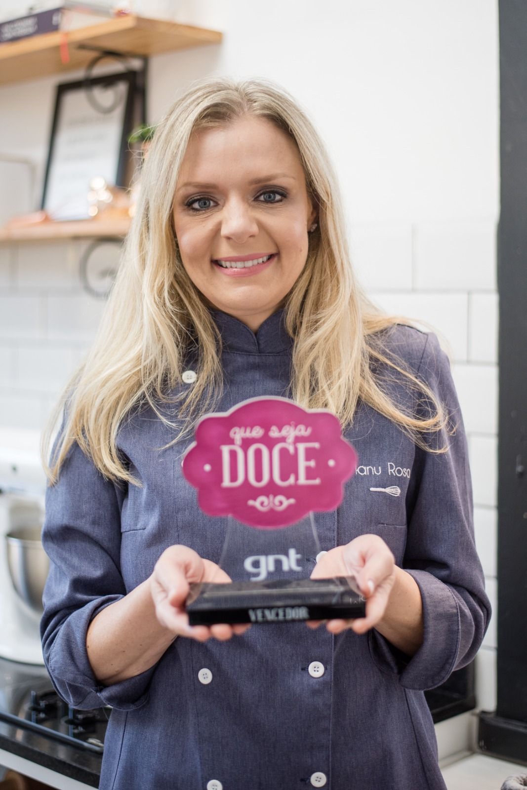 Chef Manu Rosa segurando o troféu do programa Que Seja Doce