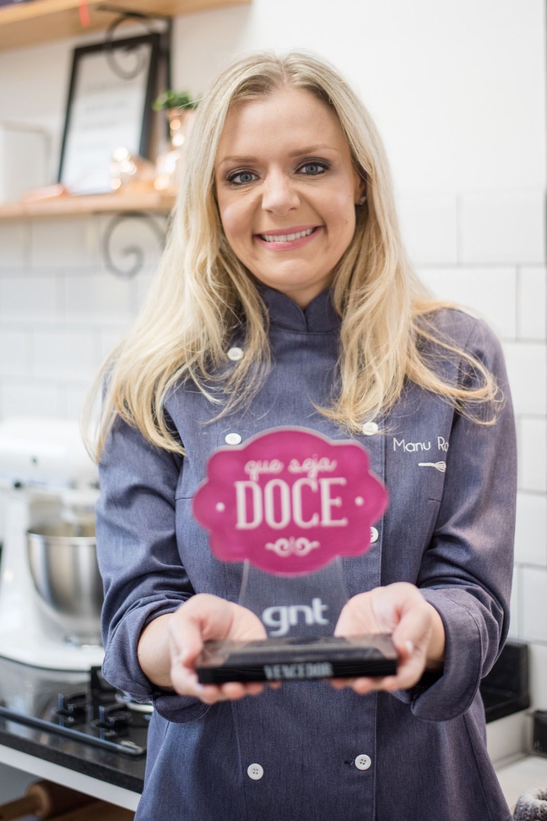 Chef Manu Rosa segurando troféu do programa Que Seja Doce