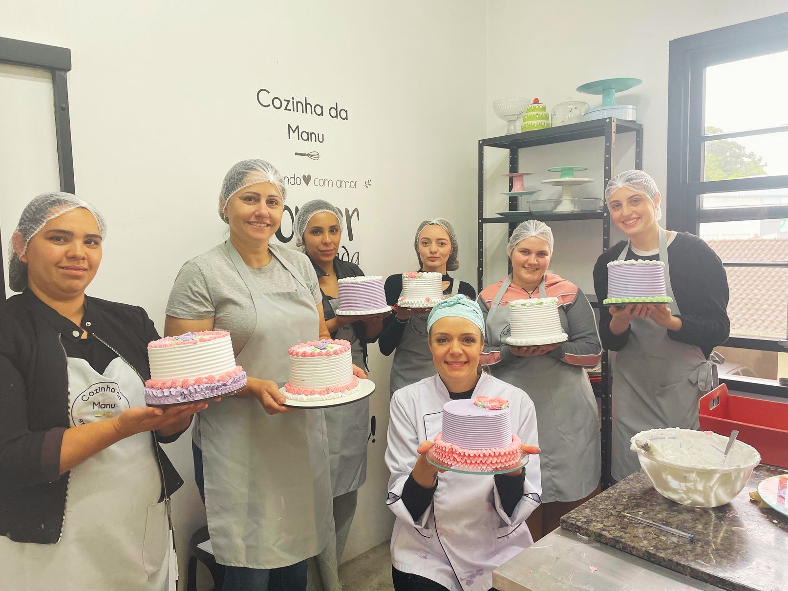 Turma reunida com bolos produzidos em curso de confeitaria